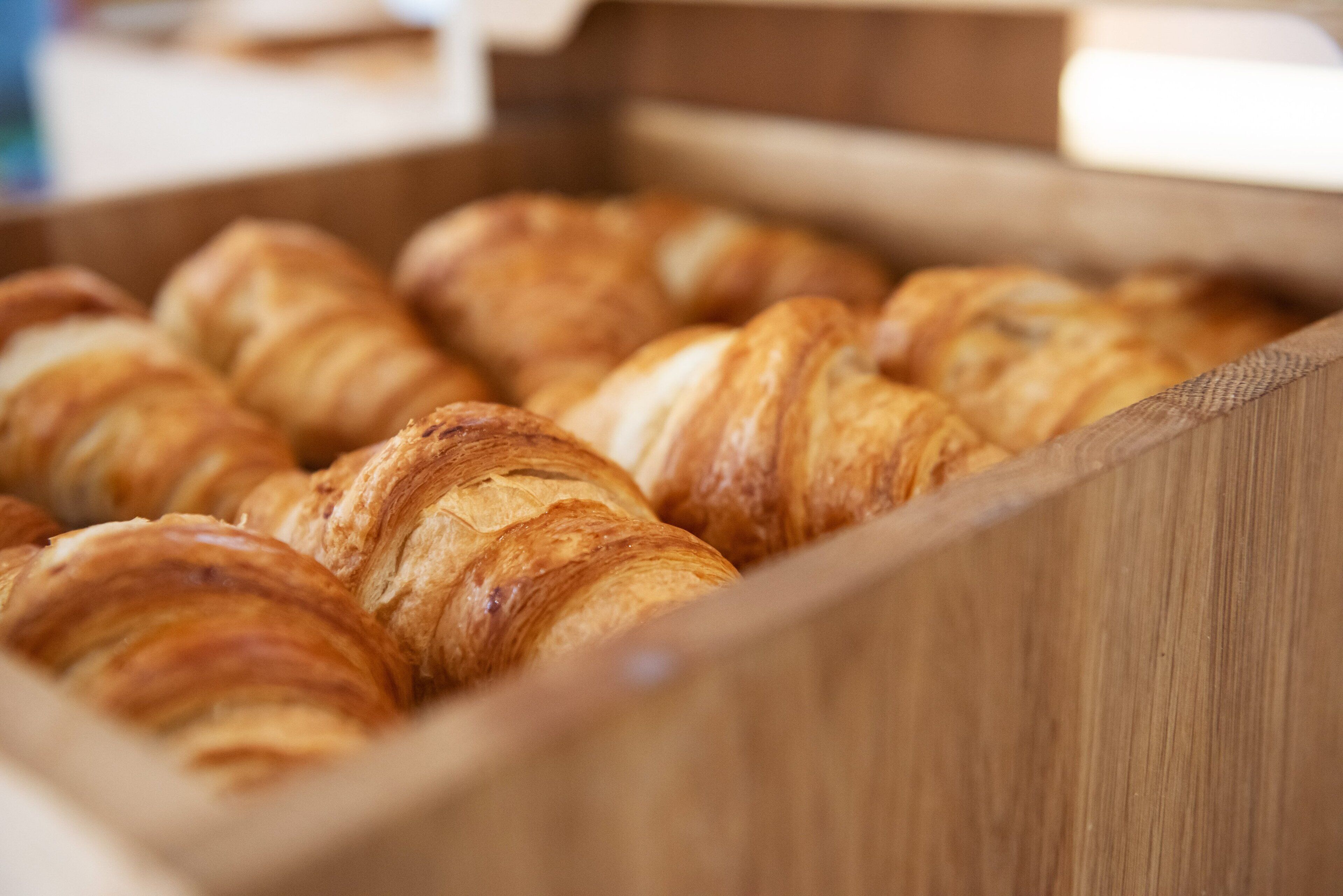 A wooden box containing several croissants.