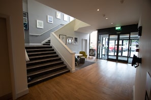 A modern interior with a staircase, a seating area, and a glass door entrance. - Holiday Inn Preston by IHG (Preston)