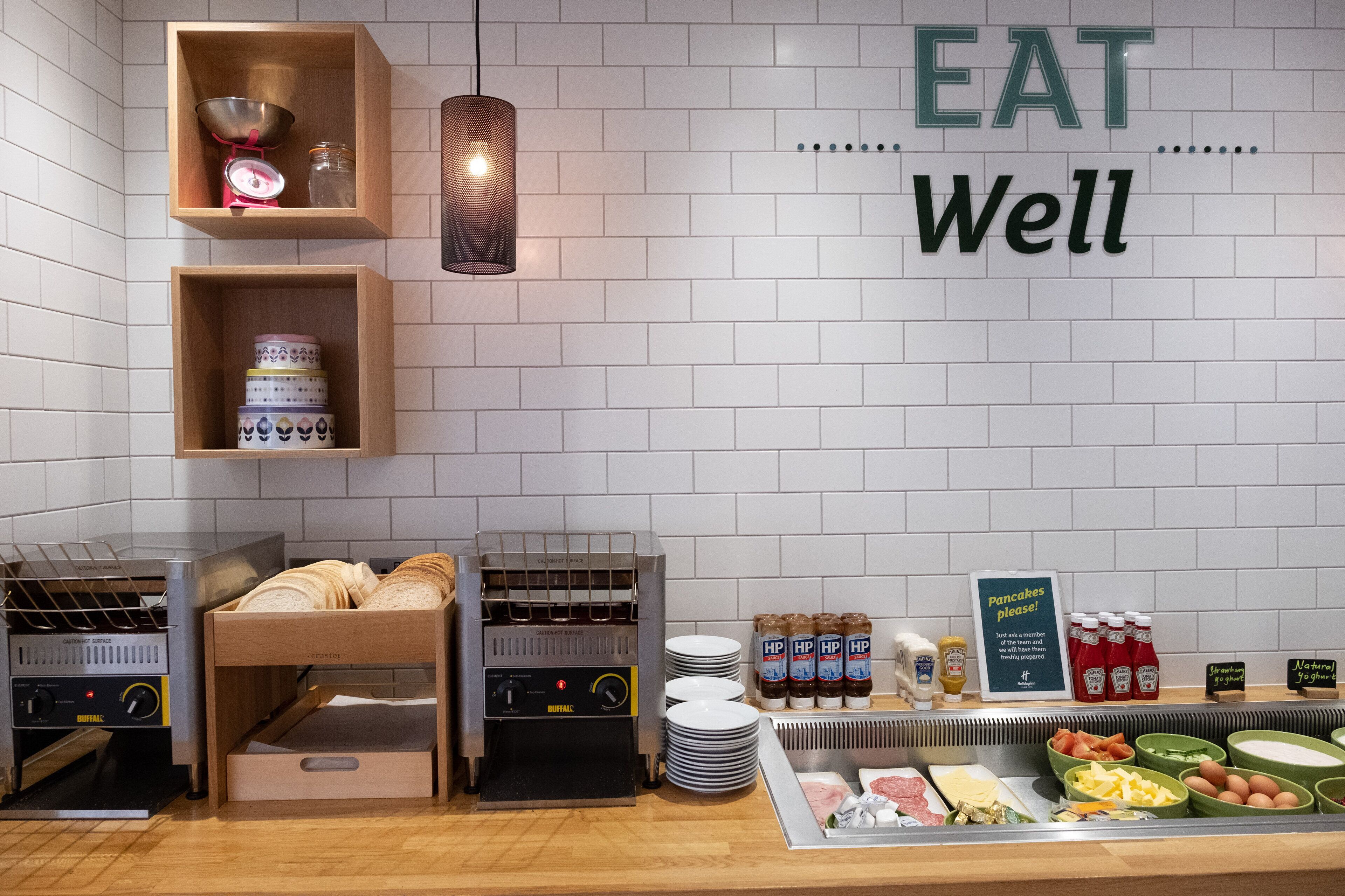 A breakfast buffet area with a variety of food items, including bread, pancakes, and condiments.
