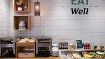 Zona de desayuno tipo buffet con una variedad de alimentos, incluyendo pan, panqueques y salsas.