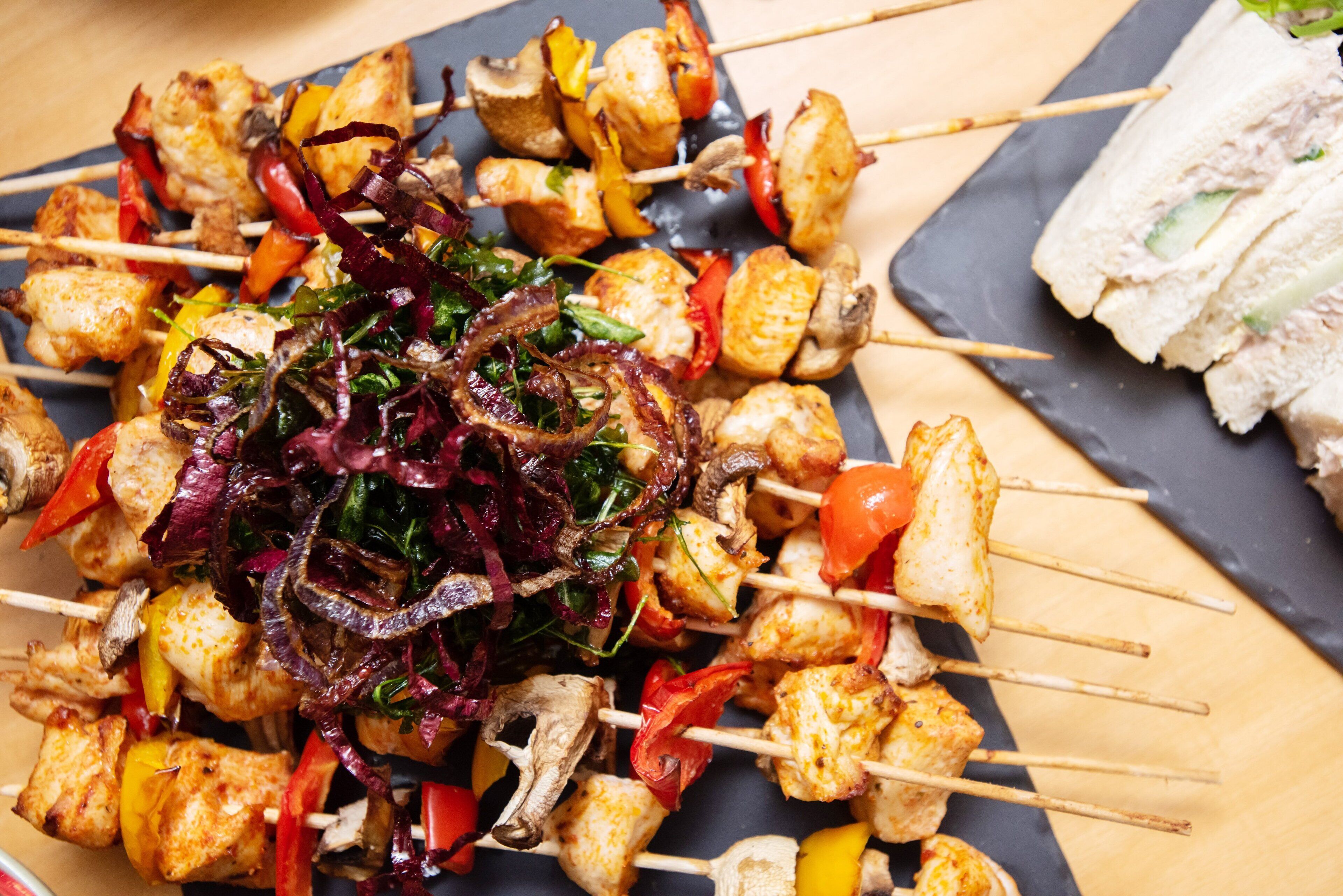 Une variété de viandes et de légumes en brochettes, notamment du poulet, des poivrons et des oignons, disposés sur une assiette.