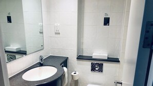 A modern bathroom with a large sink, toilet, and a mirror.
