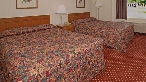 A hotel room with two beds, a window with a view, and a patterned carpet. - Gateway Inn (Petersburg)