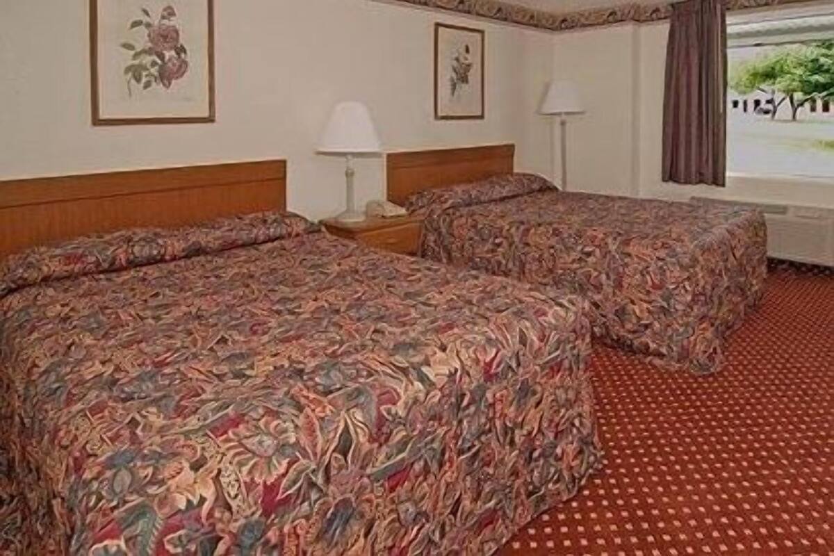 A hotel room with two beds, a window with a view, and a patterned carpet.