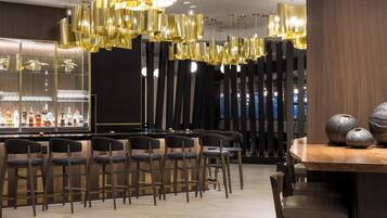 A modern bar area with high stools, a wooden table, and a bar stocked with bottles.