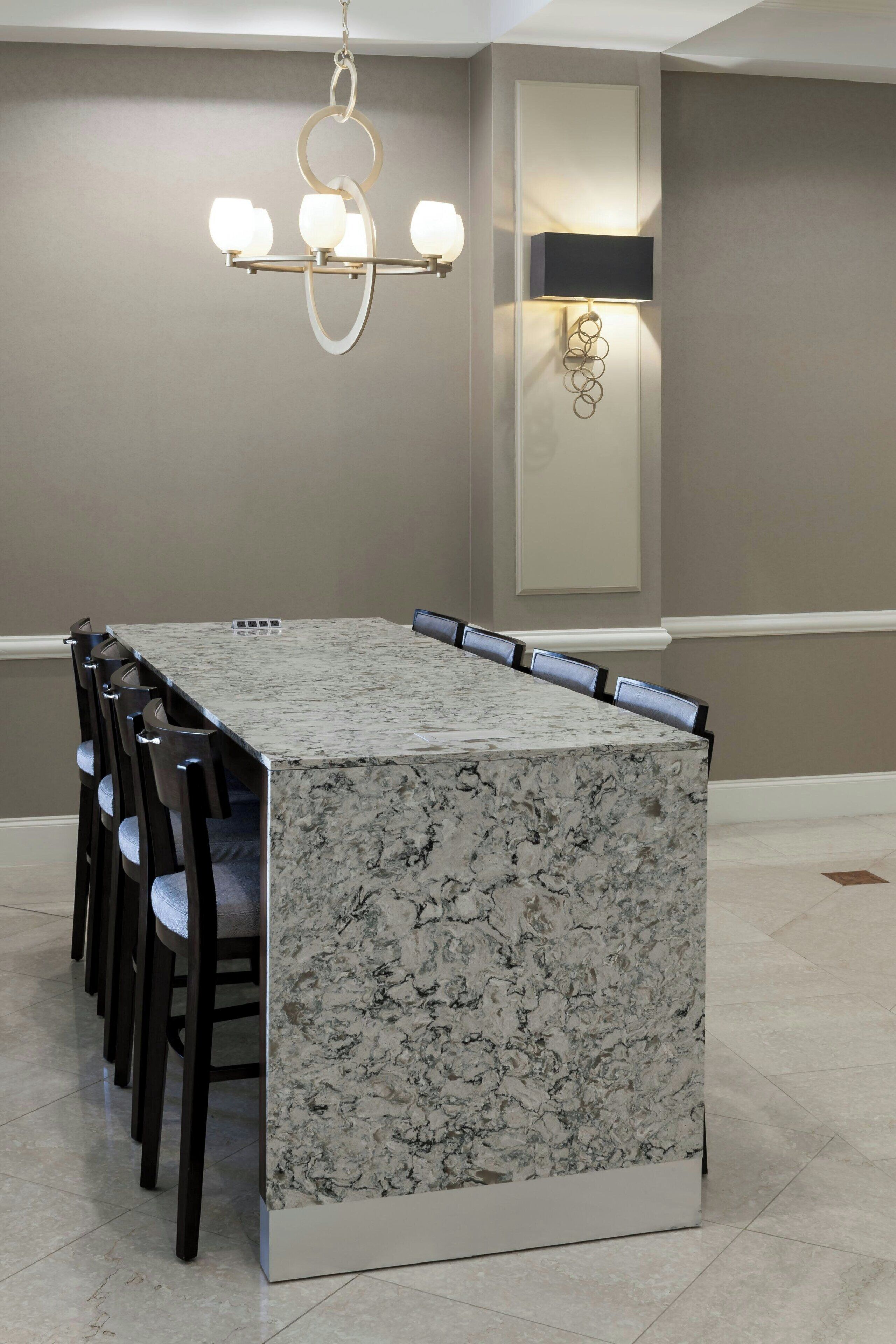 A rectangular marble-top dining table with six chairs, a chandelier, and wall-mounted lighting fixtures.
