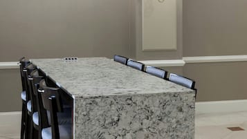 A rectangular marble-top dining table with six chairs, a chandelier, and wall-mounted lighting fixtures.