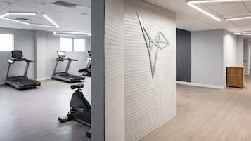 Un gimnasio moderno con cintas de correr, bicicletas estáticas y una máquina de ejercicios de pared.