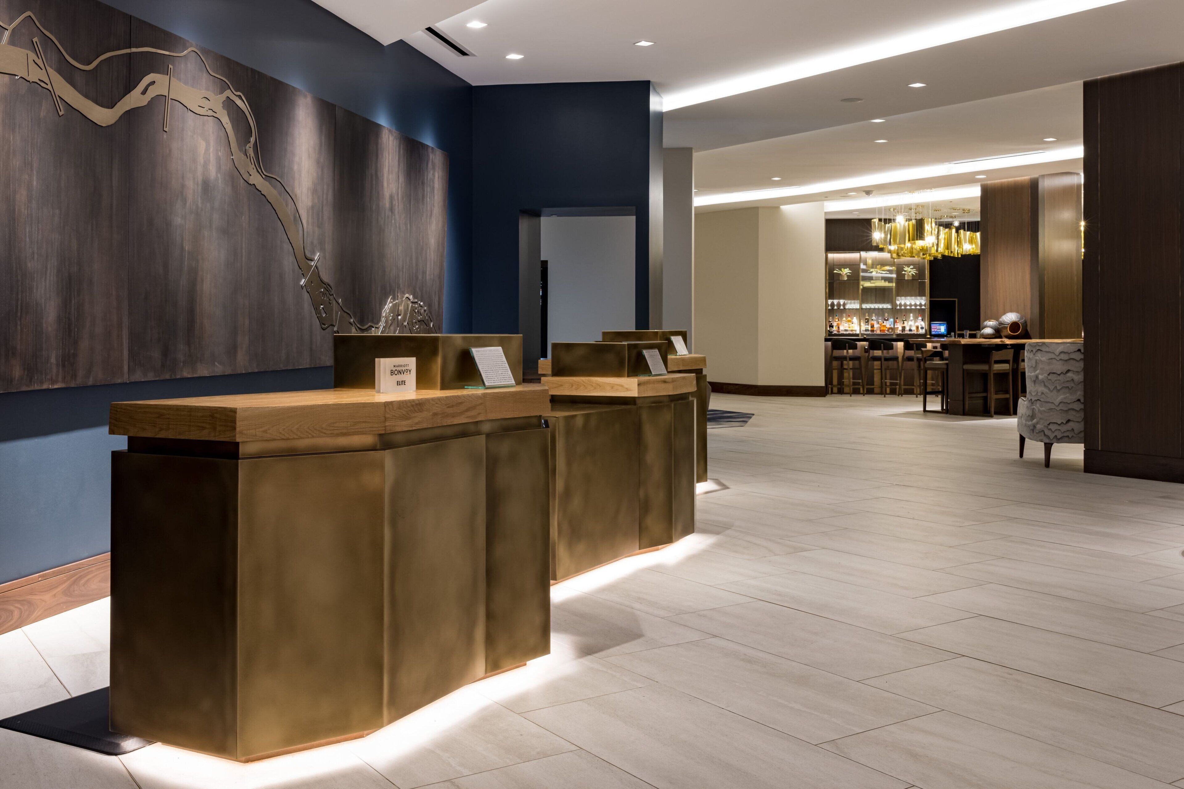Un área de recepción con diseño moderno, que incluye un mostrador de madera y una zona de bar al fondo.