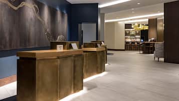 Un área de recepción con diseño moderno, que incluye un mostrador de madera y una zona de bar al fondo.