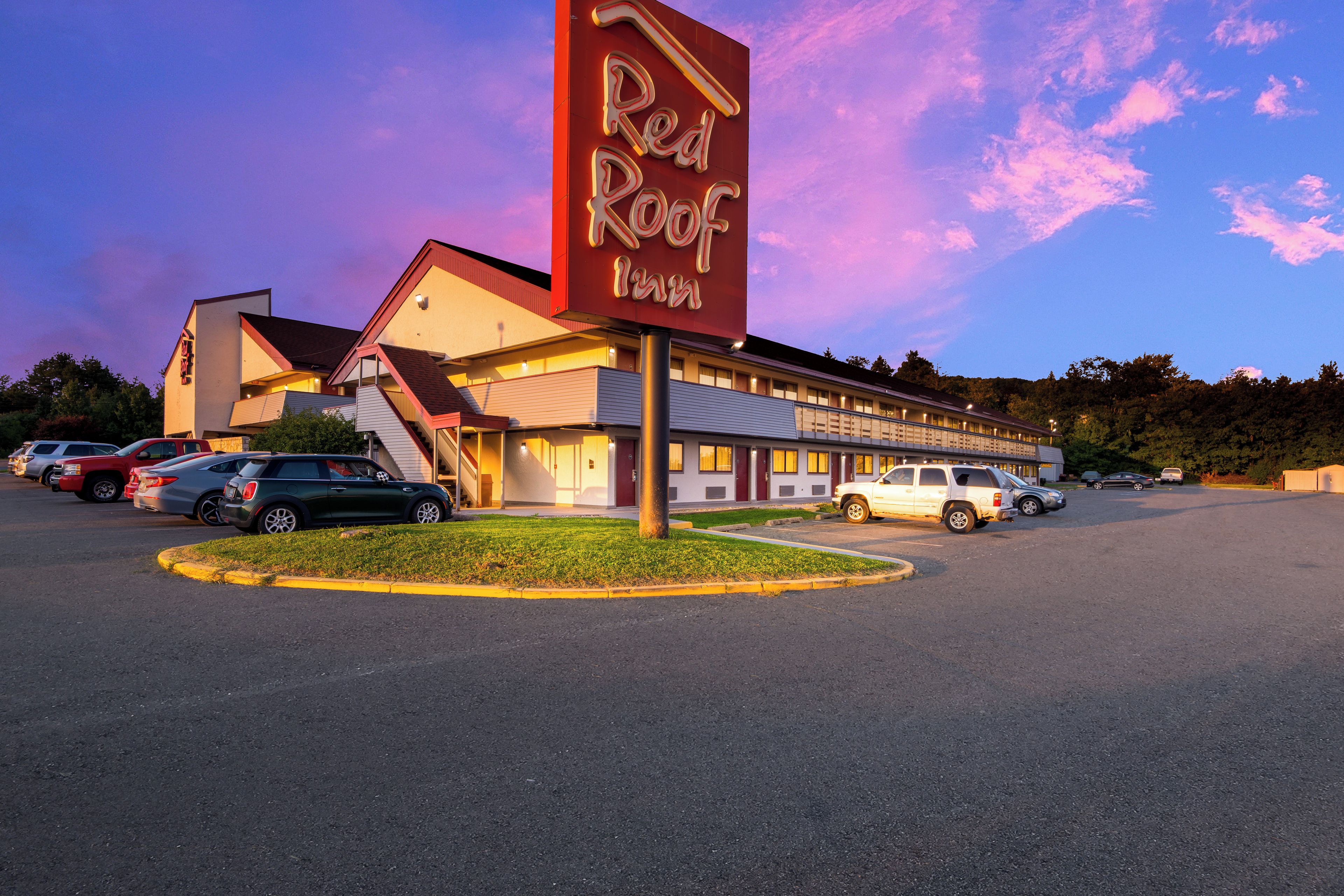 Un hôtel Red Roof Inn avec un parking et plusieurs voitures garées devant.
