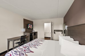 Een hotelkamer met een bed, een bureau, een televisie, een deur en een spiegel.