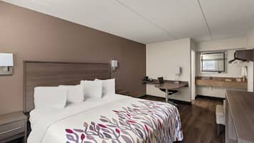 A hotel room with a bed, a desk, a chair, and a bathroom.