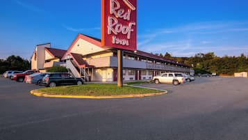 A Red Roof Inn with a parking lot and a building with a red roof.