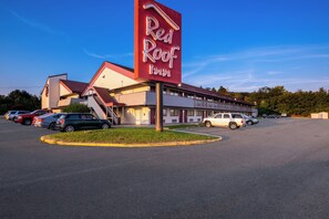 Een Red Roof Inn met een parkeerplaats en een gebouw met een rood dak.
