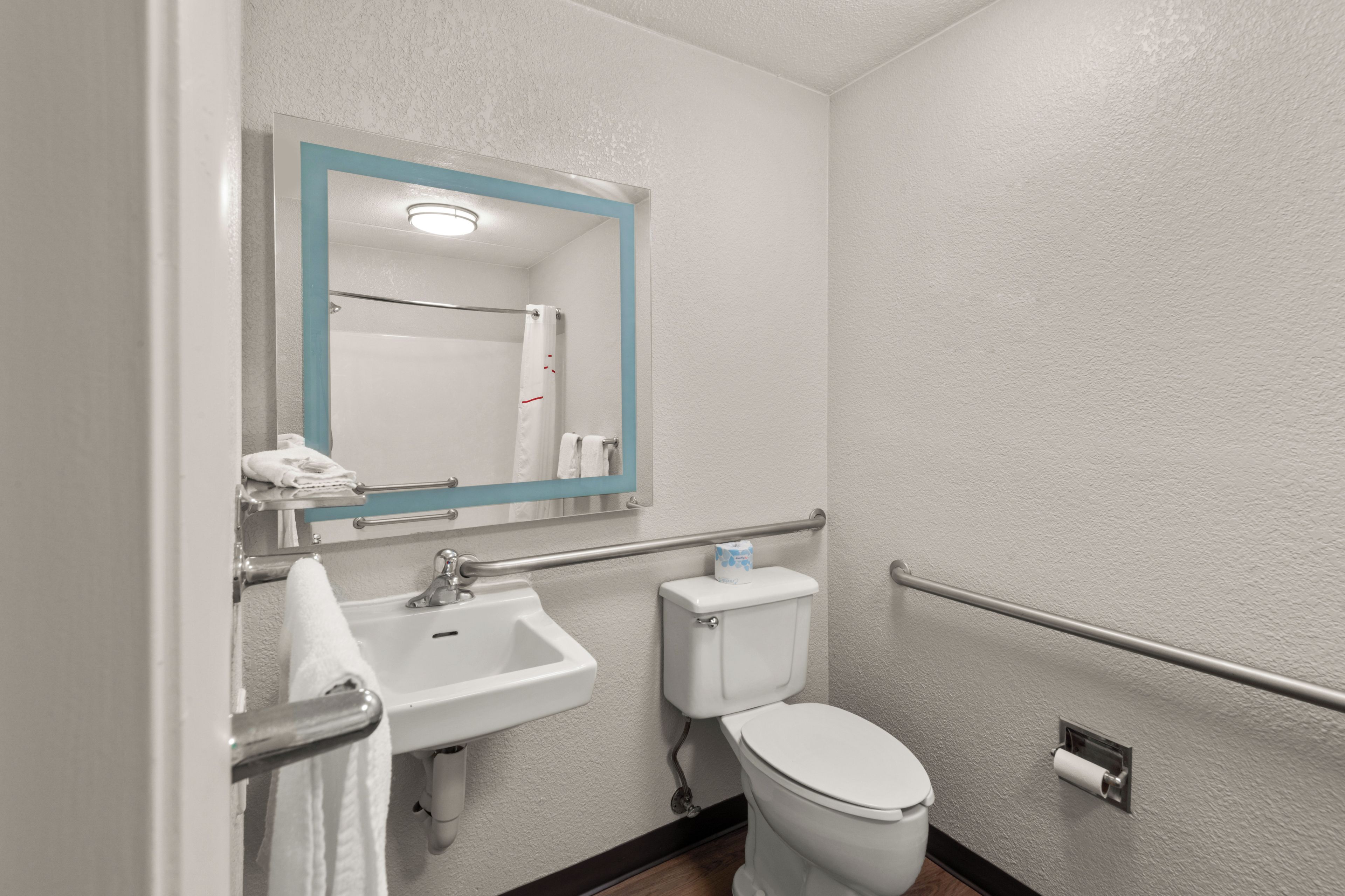 Un baño con lavamanos blanco, inodoro y espejo con marco azul.