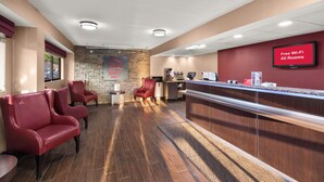 Een hotellobby met een receptiebalie, een zithoek en een bord dat gratis Wi-Fi aangeeft.