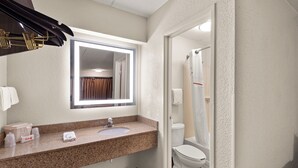 Een badkamer met een granieten aanrechtblad, een wastafel, een spiegel, een toilet en een douchegordijn.