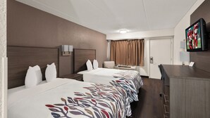 Een hotelkamer met twee bedden, een bureau, een televisie en een deur.