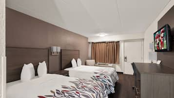 Ein Hotelzimmer mit zwei Betten, einem Schreibtisch, einem Fernseher und einer Tür.