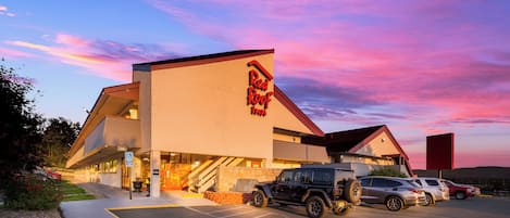 Een hotel met een bord waarop 'Red Roof Inn' staat en een parkeerplaats met meerdere voertuigen.
