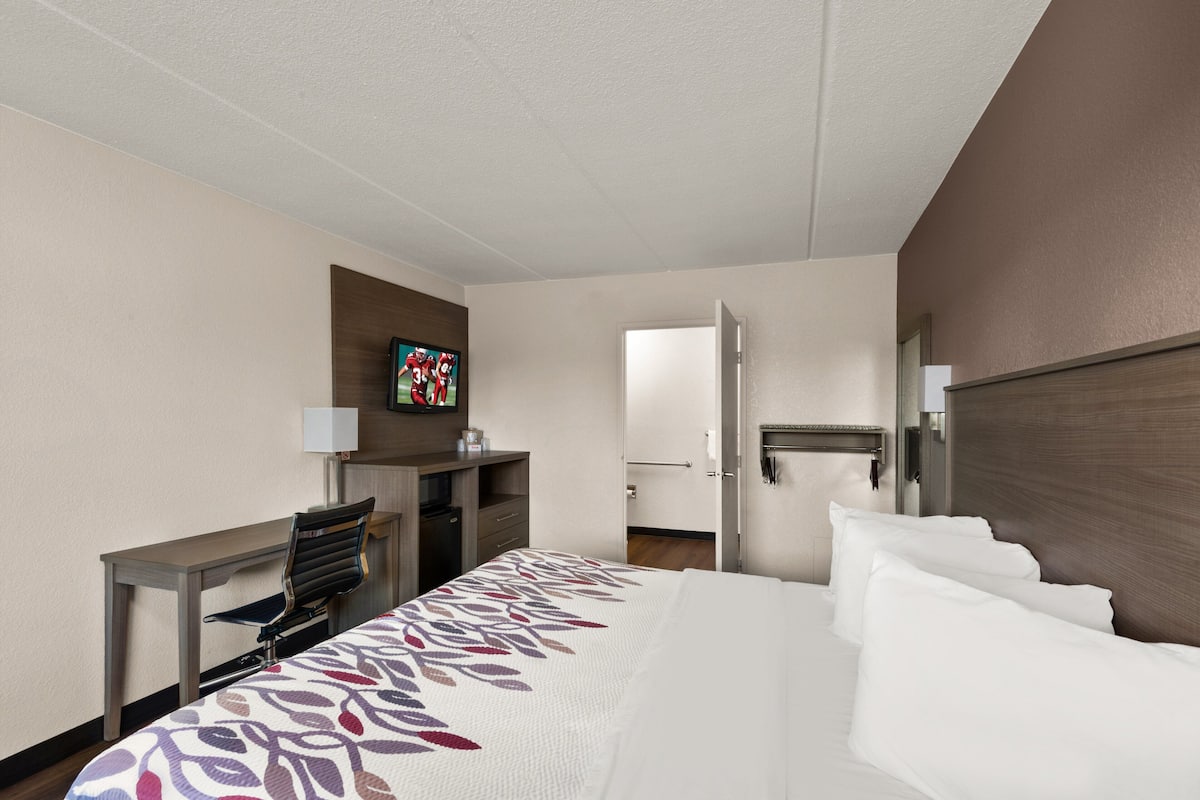 Een hotelkamer met een bed, een bureau, een televisietoestel en een deur naar een andere kamer.