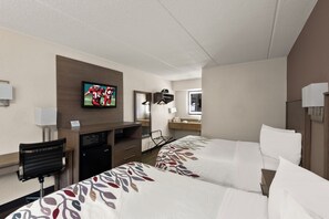 Een hotelkamer met twee bedden, een televisie, een bureau, een magnetron, een spiegel en een badkamer.