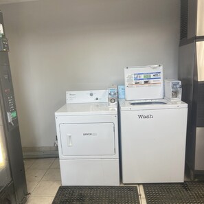 Une buanderie équipée de deux machines à laver et de deux sèche-linge Whirlpool blancs, d’un panneau de commande et d’une étiquette indiquant un prix de 1,00 $.