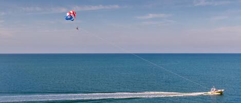 A parasail over a calm sea with a speedboat creating a wake.