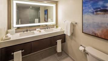Une salle de bain moderne avec un grand miroir, deux lavabos, des toilettes et un tableau accroché au mur.
