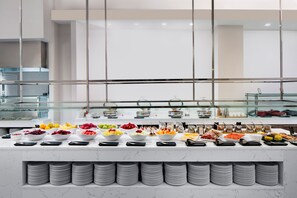 Un buffet proposant une variété de plats et des saladiers remplis de fruits et de légumes.