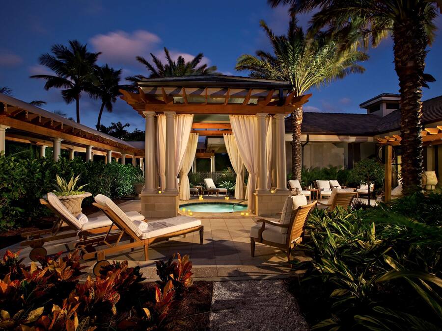 A poolside area with lounge chairs, a pergola, and a pool.