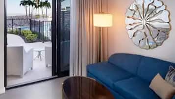 A modern living room with a blue sofa, a decorative wall piece, and a view of palm trees through a glass door.