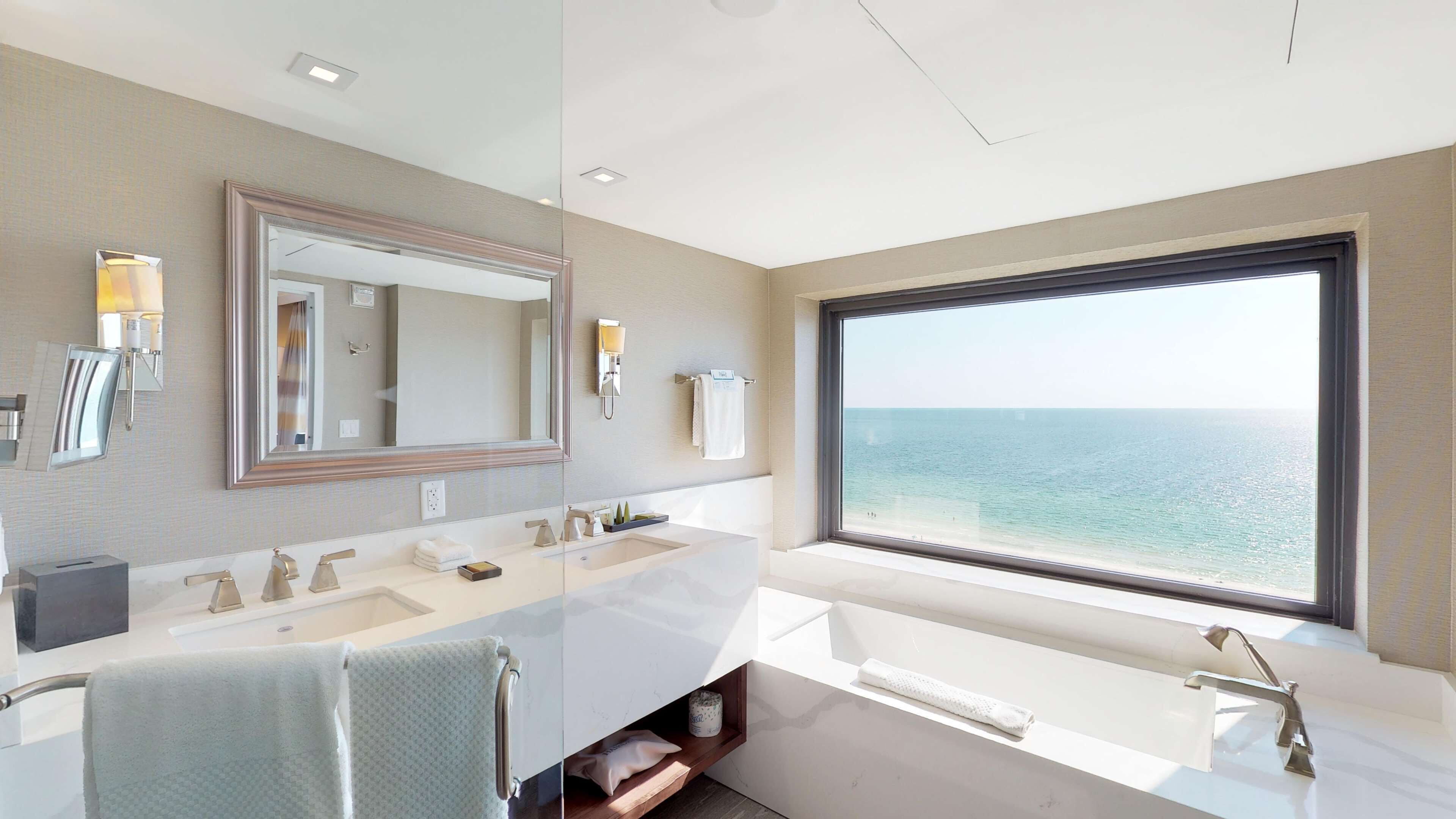 A modern bathroom with a large window, a dual sink vanity, and a large mirror.