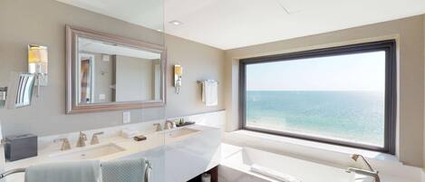 A modern bathroom with a large window, a dual sink vanity, and a large mirror.