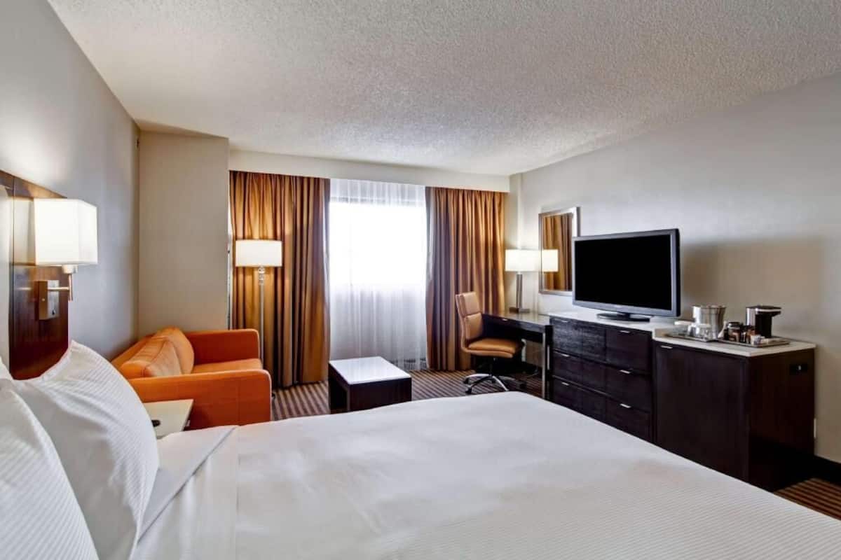 Une chambre d’hôtel comprenant un lit, un bureau avec une chaise, une télévision et une petite table.