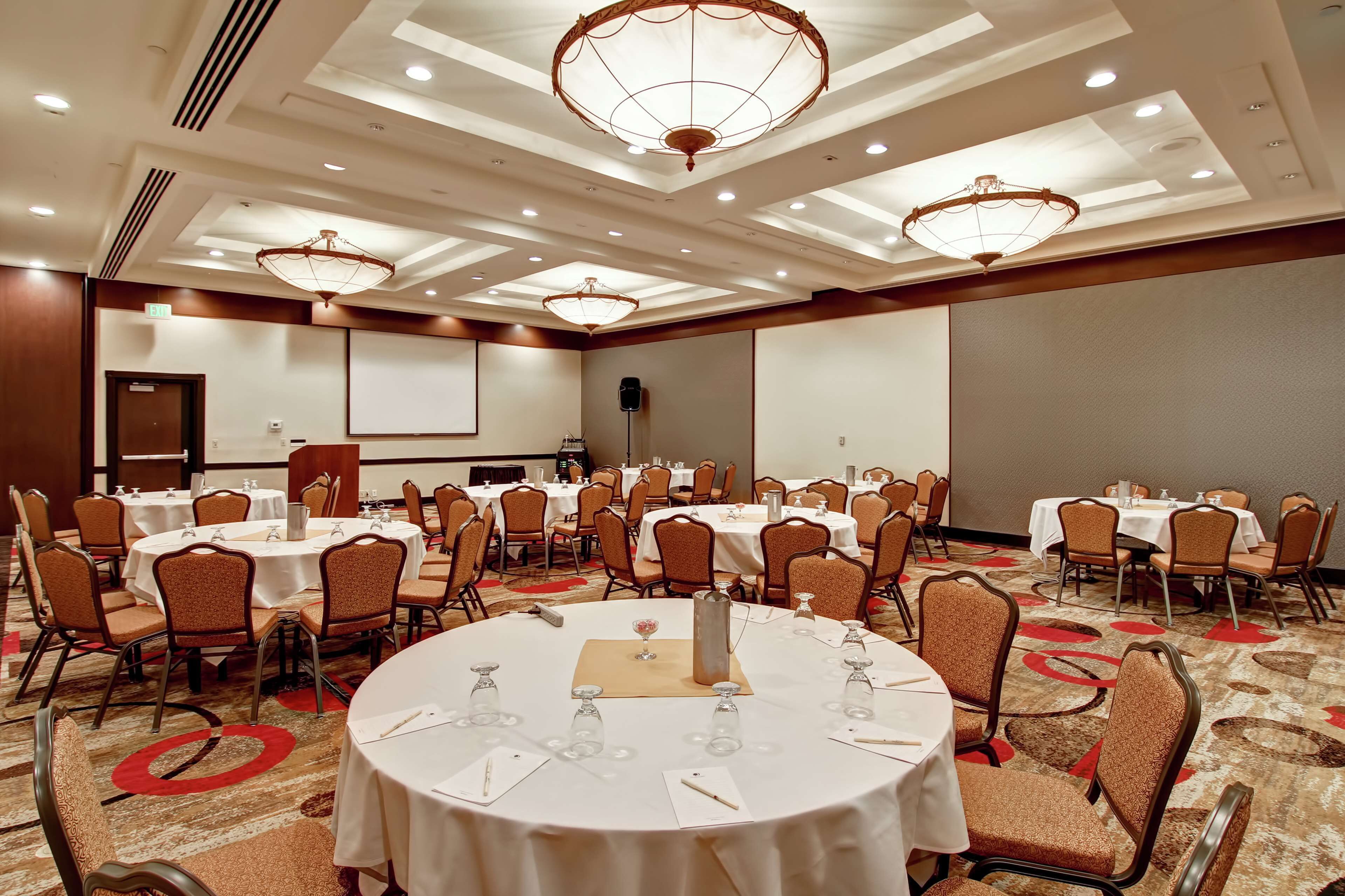 A conference room with round tables, chairs, and a large screen.