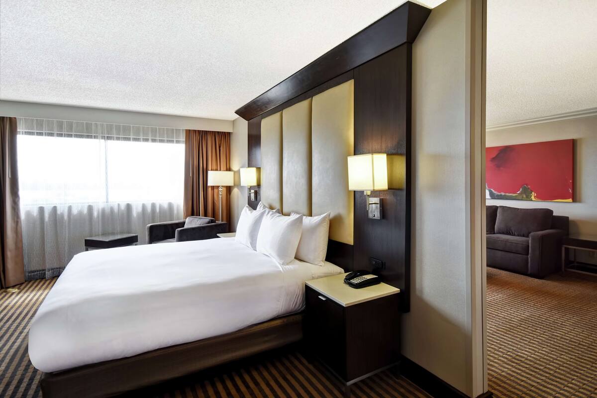 A hotel room with a large bed, bedside lamps, a desk, and a couch.