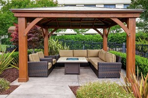 A covered outdoor seating area with a wooden pergola, cushioned sofas, and a central coffee table.
