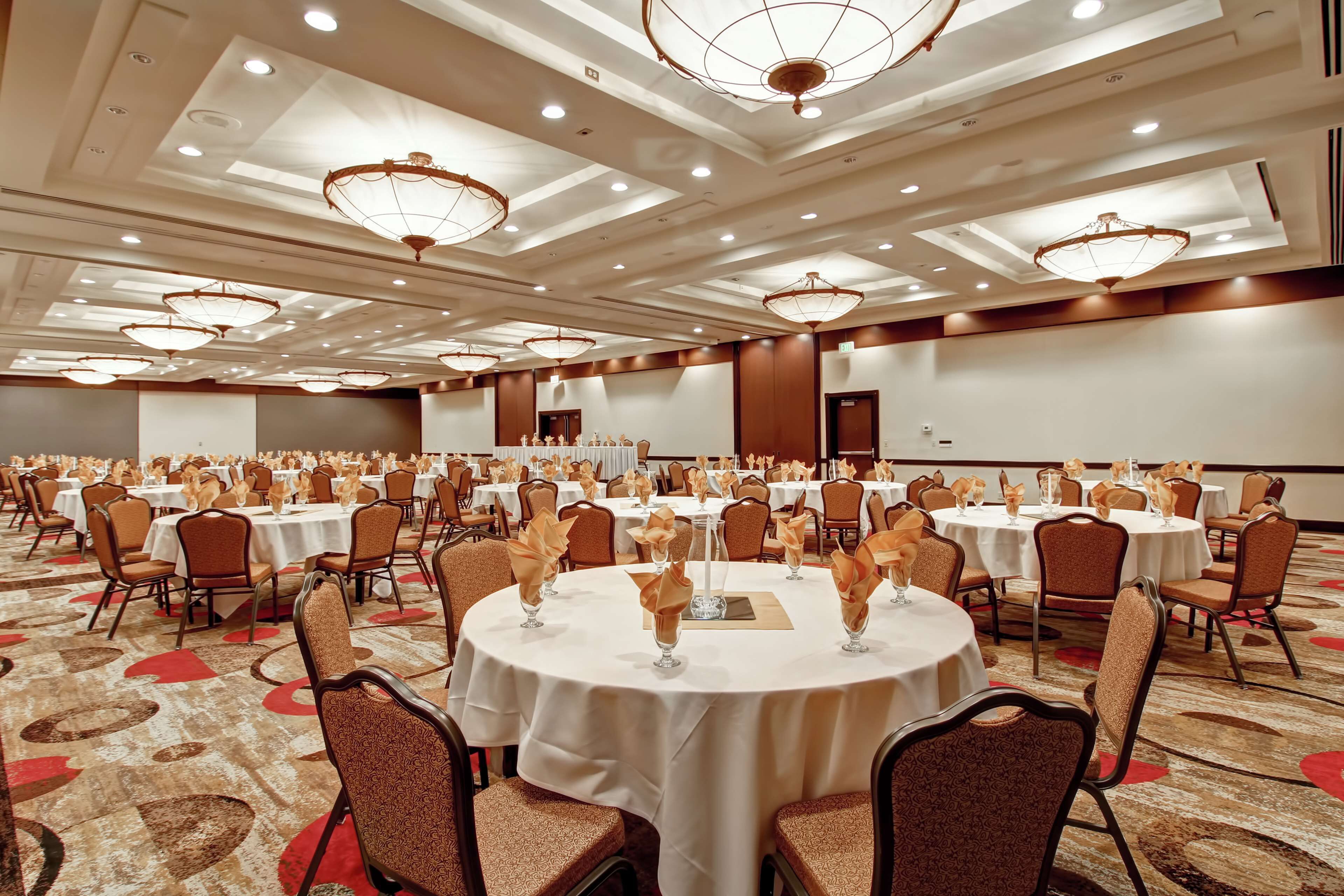 Un salón de banquetes con mesas redondas, sillas y candelabros.