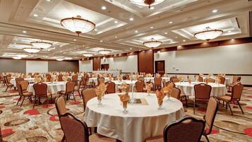 Un salón de banquetes con mesas redondas, sillas y candelabros.