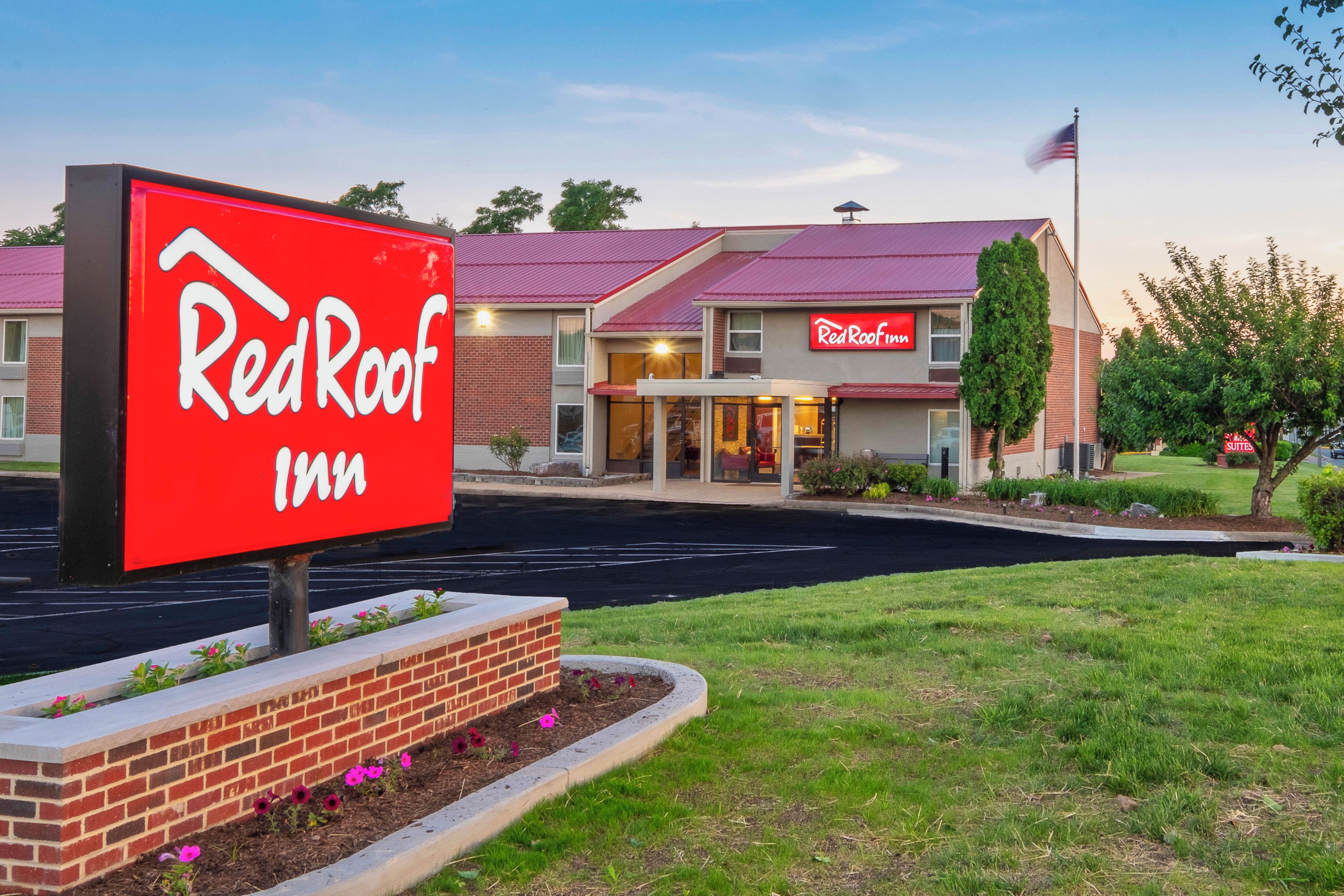 Un hotel Red Roof Inn con un letrero rojo llamativo, fachada de ladrillo y estacionamiento.
