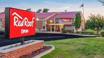 Un hotel Red Roof Inn con un letrero rojo llamativo, fachada de ladrillo y estacionamiento.
