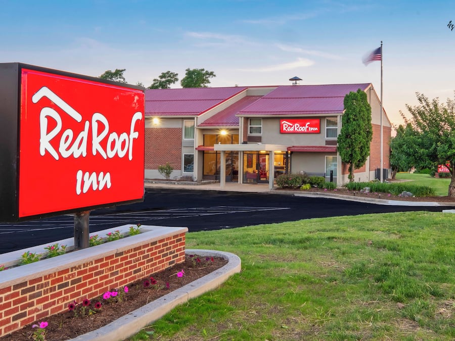 A Red Roof Inn with a prominent red sign, brick facade, and a parking lot.