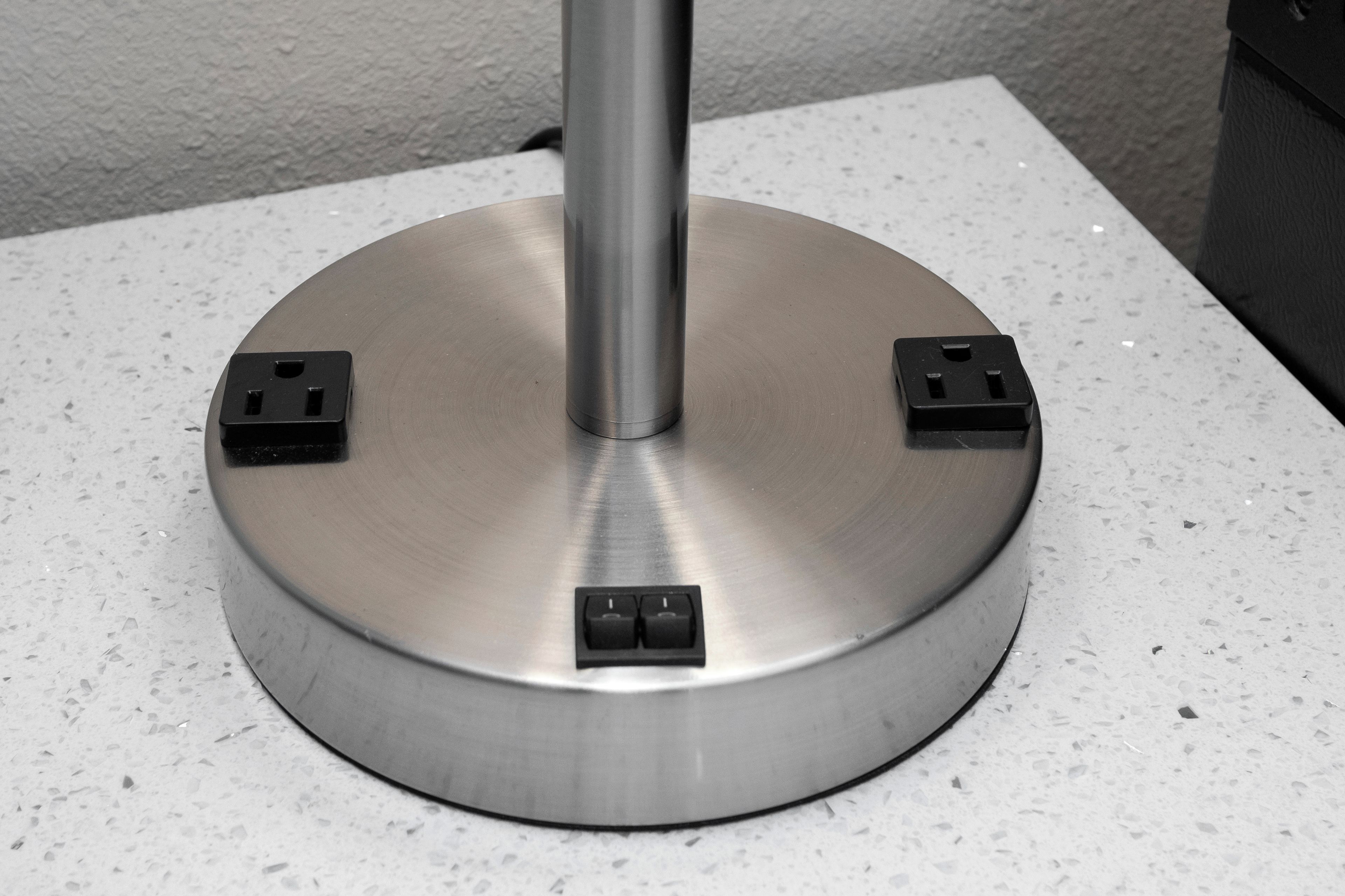 Une base métallique circulaire dotée de quatre prises électriques noires.