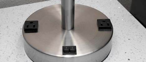 Una base metálica circular con cuatro tomas de corriente negras.