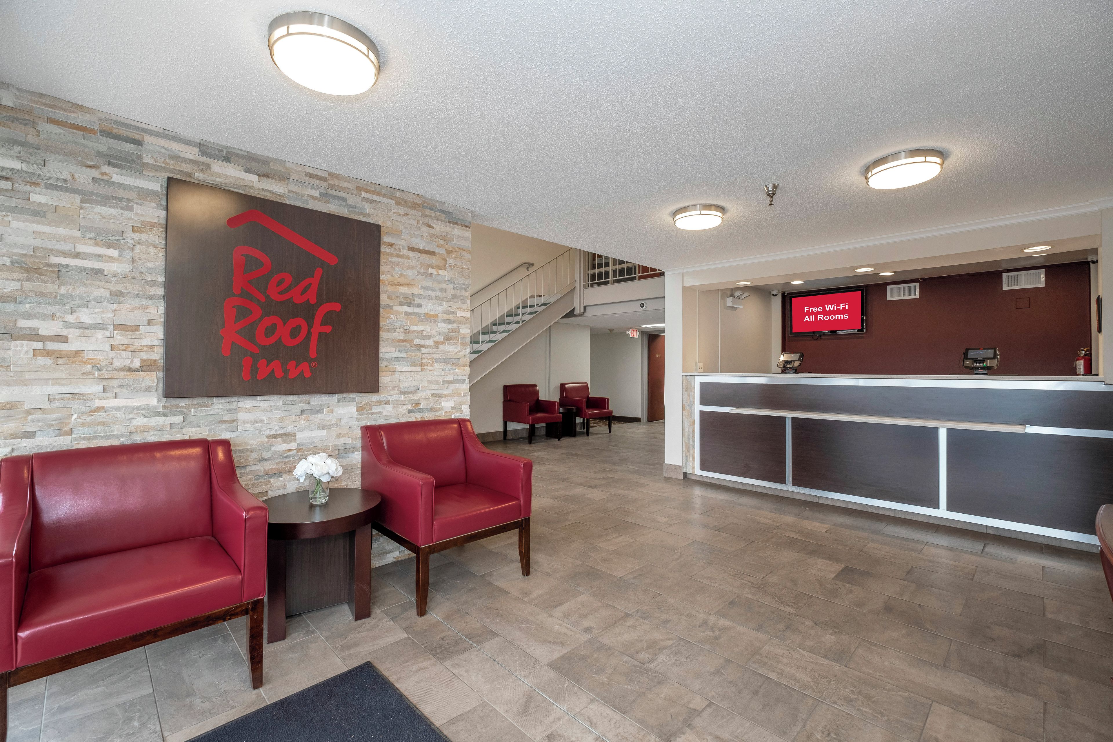A Red Roof Inn lobby with a reception desk, a staircase, and seating area.
