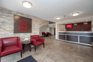 A Red Roof Inn lobby with a reception desk, a staircase, and seating area.