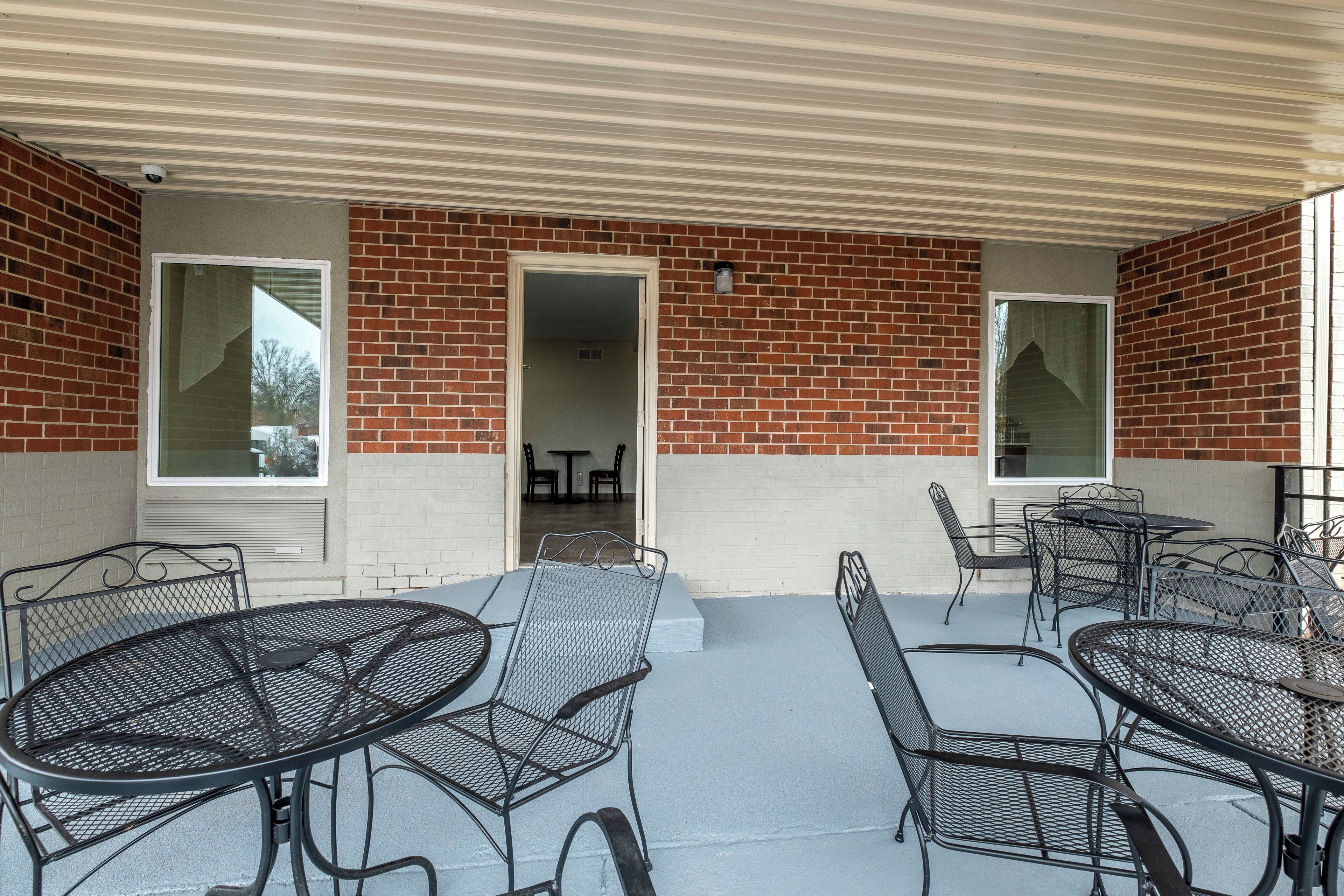 A covered patio area with outdoor seating and a brick wall.