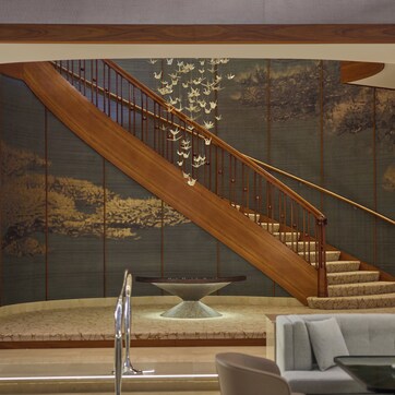 A modern interior with a wooden staircase, a stone table, and a light-colored sofa.